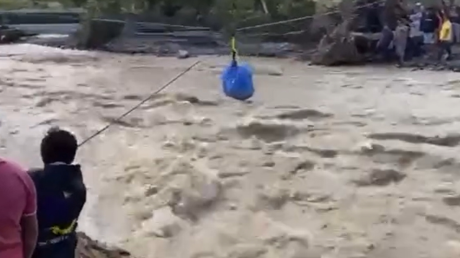 Voluntarios usan una tirolesa para cruzar víveres sobre el río desbordado en Hidalgo.