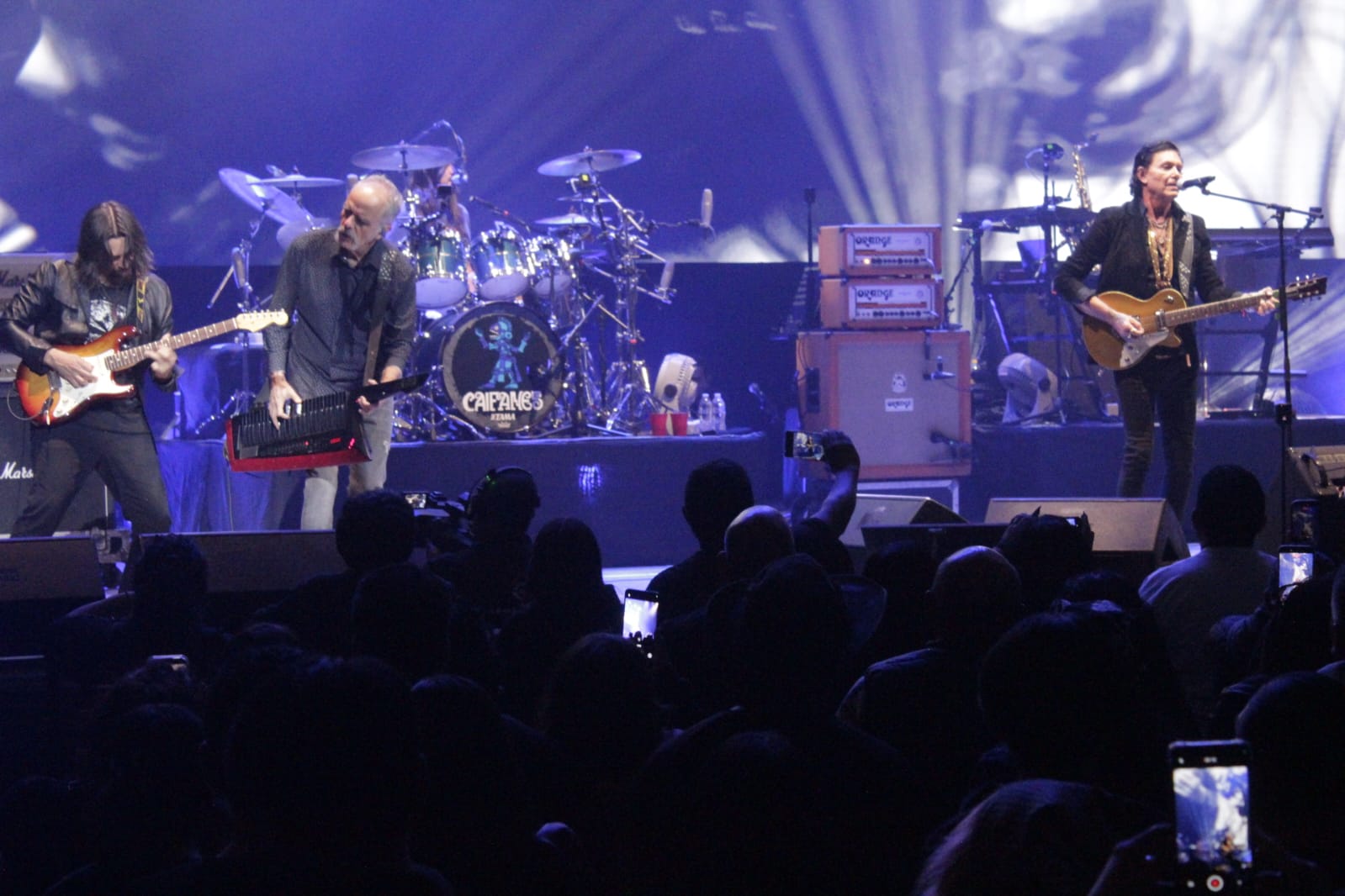 Caifanes durante una presentación en vivo con escenario iluminado.